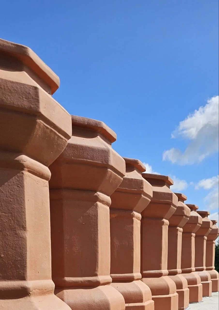 Row of new terracotta chimney pots against blue sky