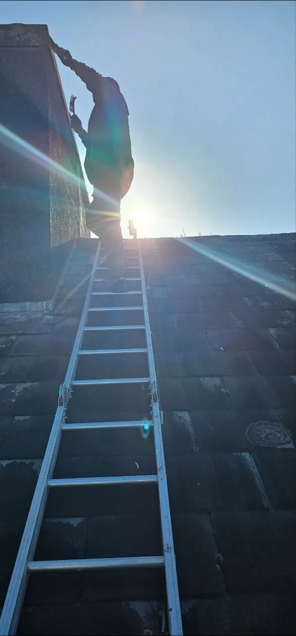 Roofer climbing a ladder at sunrise