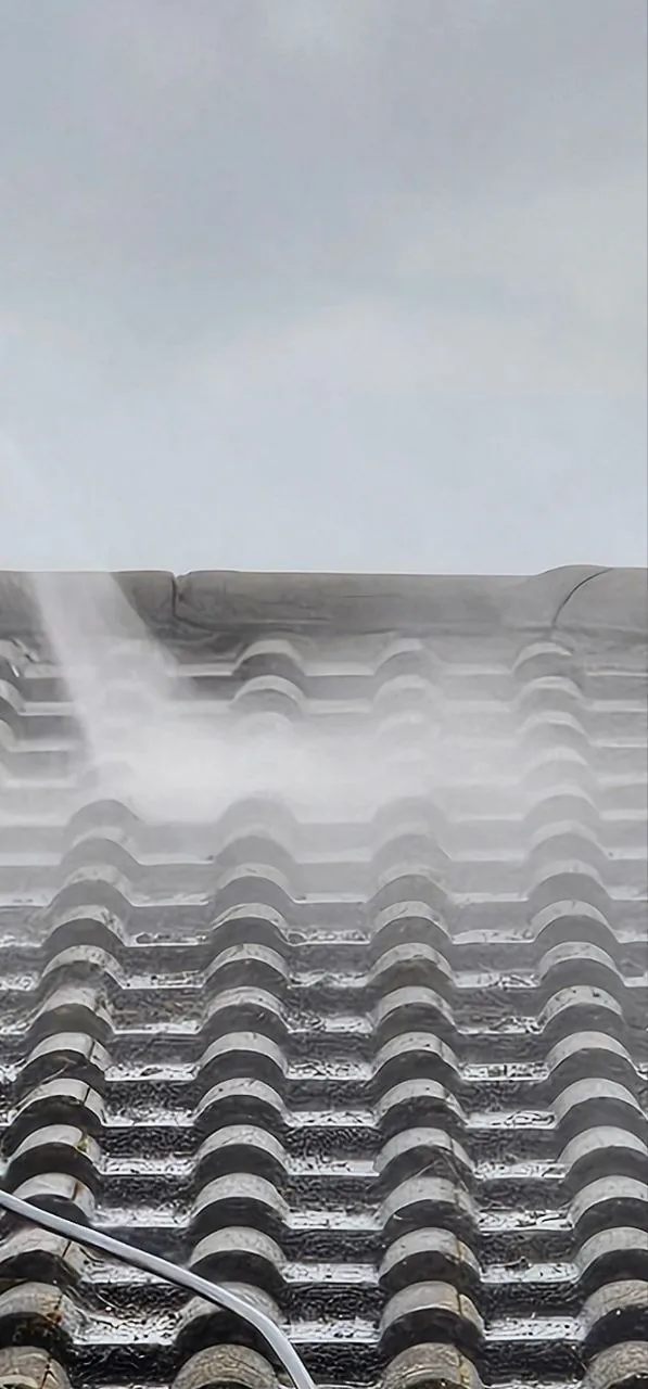 Tiled roof being power washed before painting