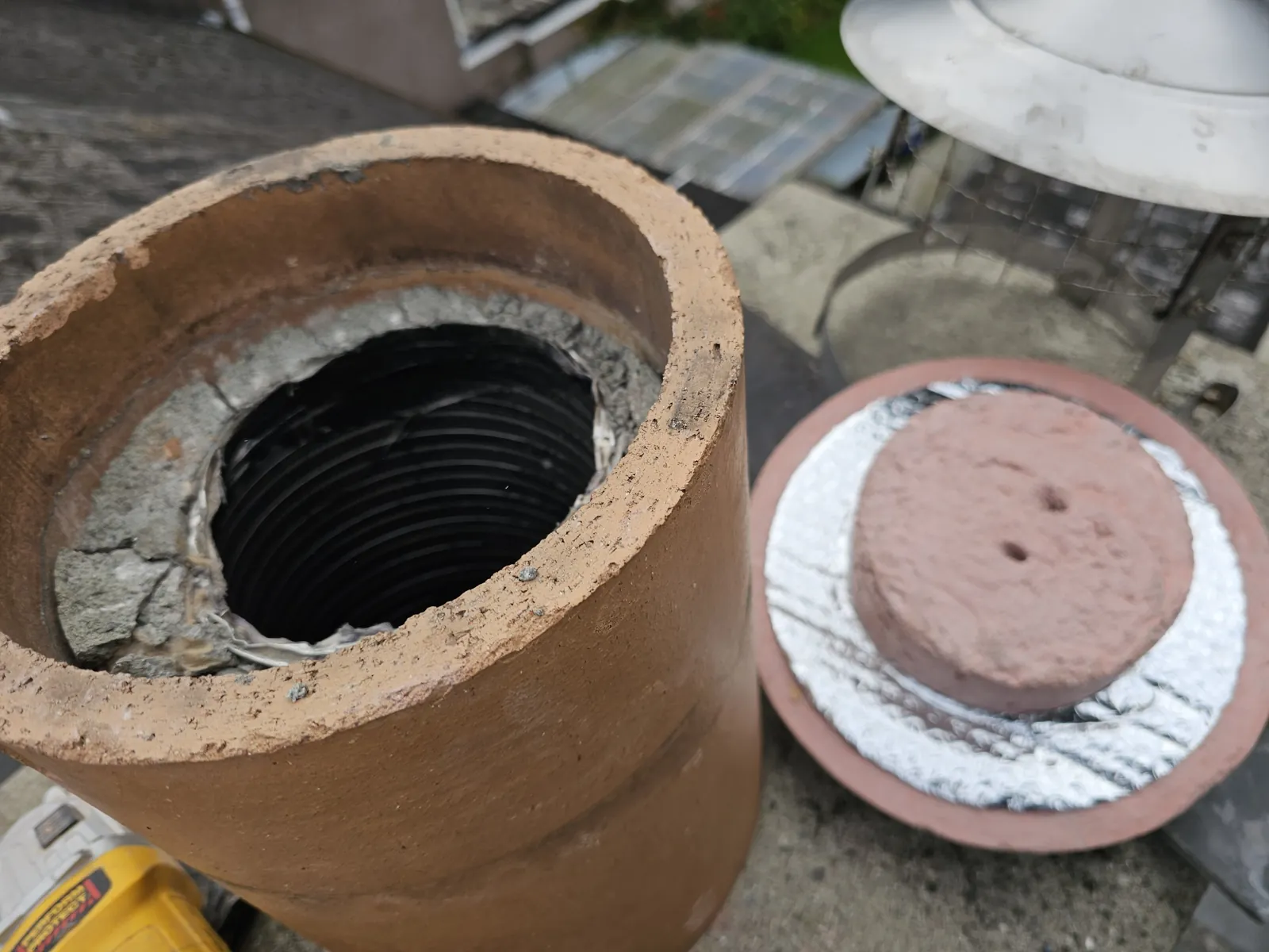 Flexible flue liner sealed into the top of a clay chimney pot