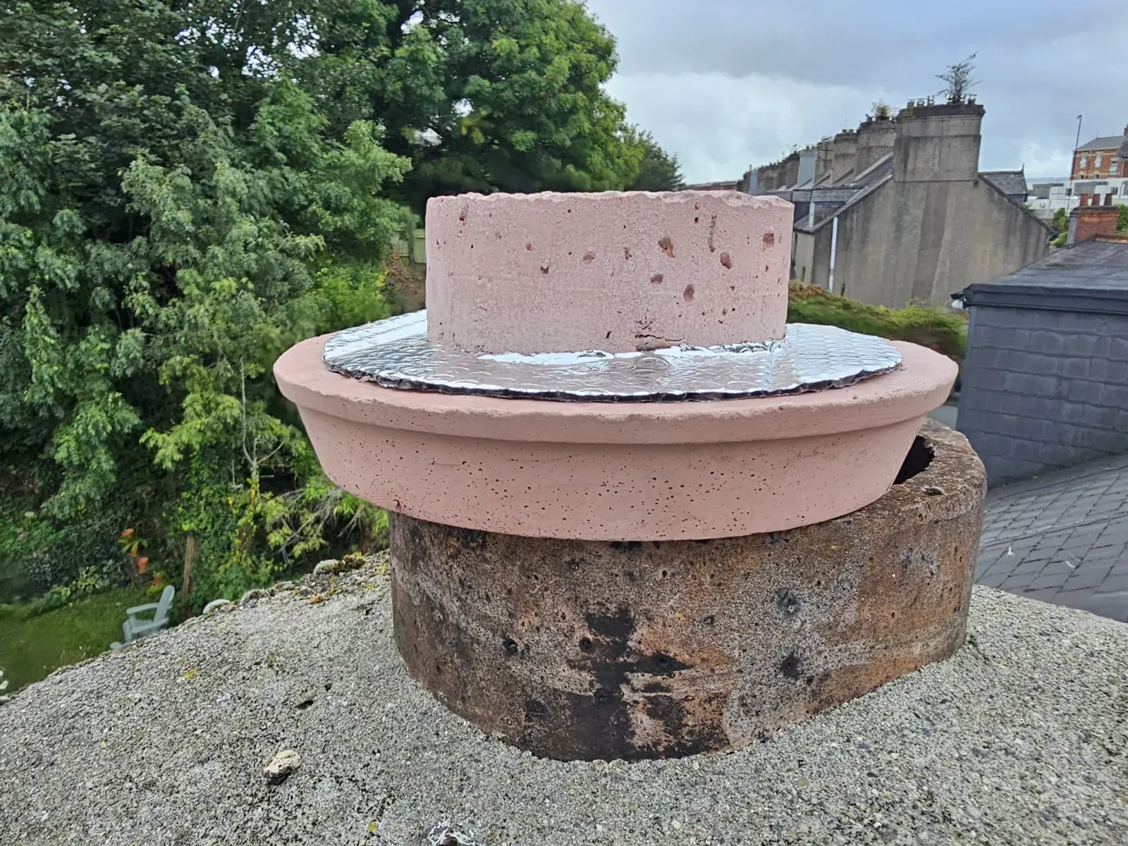 Vented cap with a foil insulation layer fitted on a disused chimney pot