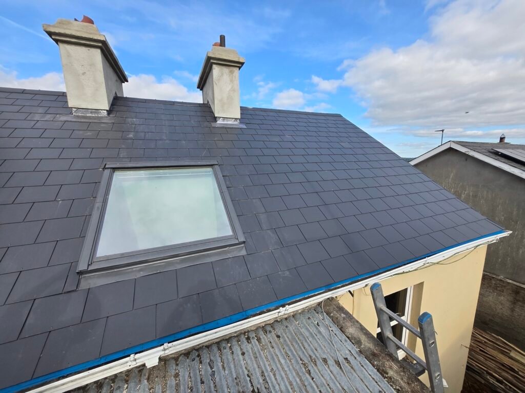 Lead-flashed rooflight and chimneys on a completed slate roof