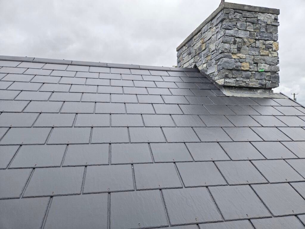 Lead flashing to a stone chimney on a completed slate roof