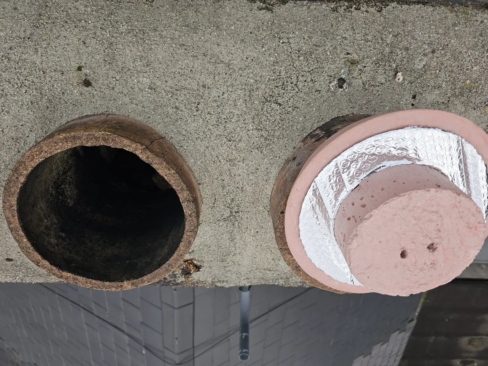 An open chimney pot beside a disused pot that has been capped