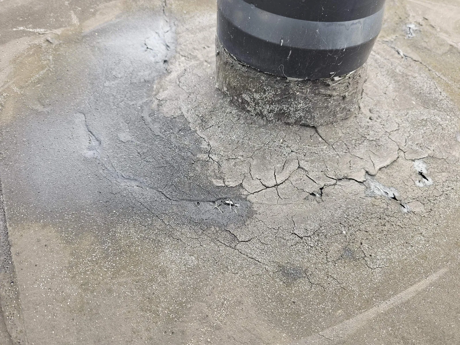 Cracked and failed flat roof coating around a vent pipe, a common cause of leaks
