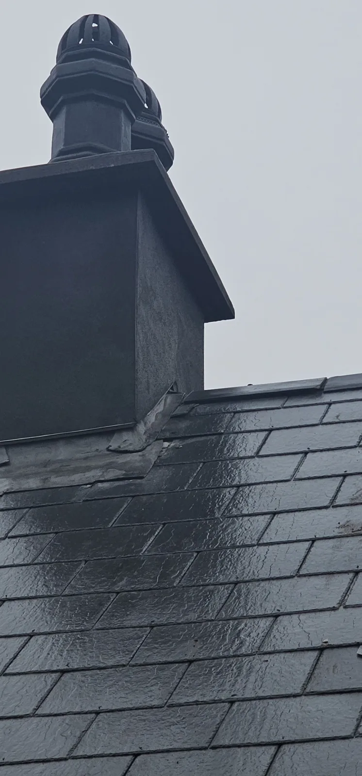 Lead flashing and soakers around a chimney on a slate roof, after rain