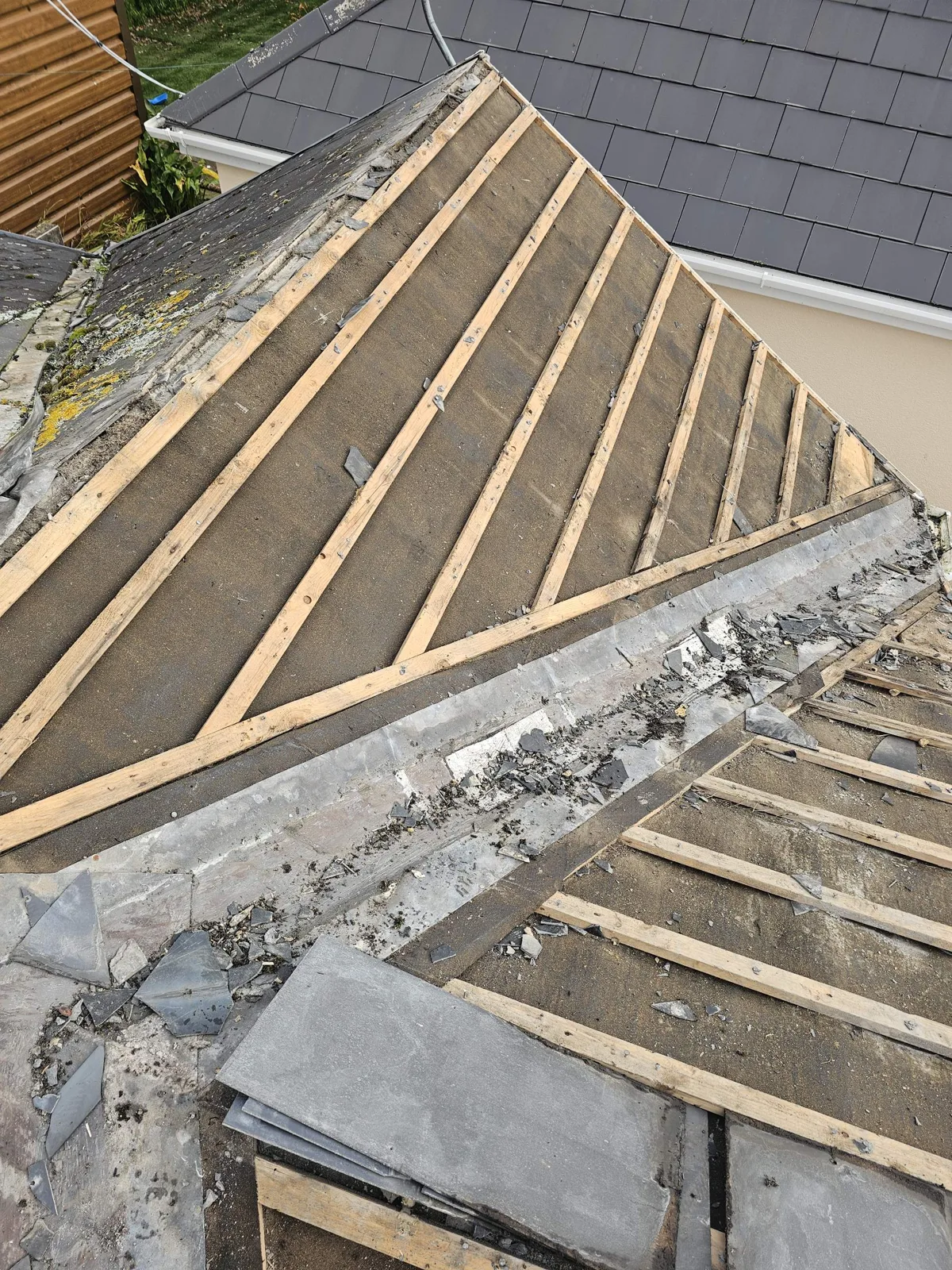Old slate roof stripped to the battens and felt, showing the lead valley before replacement